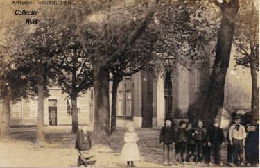 De nieuwgebouwde pastorie aan de markt. In de deuropening van zijn winkel staat bakker Joosse.