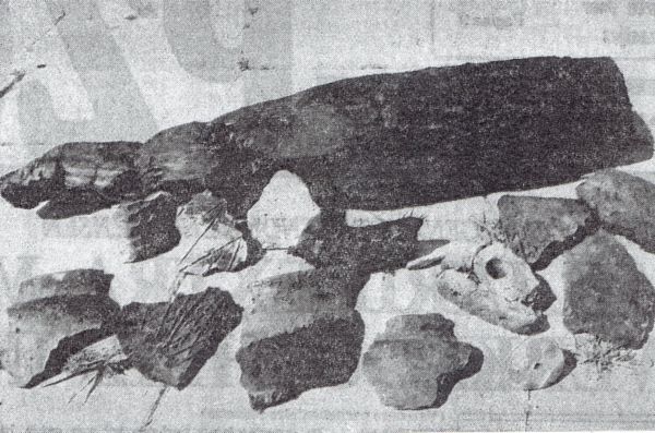 Oudheidkundige vondsten uit de ijzertijd in het uitbreidingsplan Brakenburg. Op de achtergrond een van de houten palen. Links en rechts enkele potscherven en in het midden het spinsteentje en het fragment van een weefgetouw.